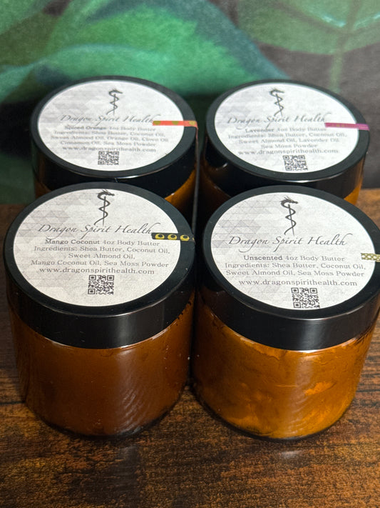 Four amber-colored jars of all natural sea moss body butter with black lids on a wooden surface