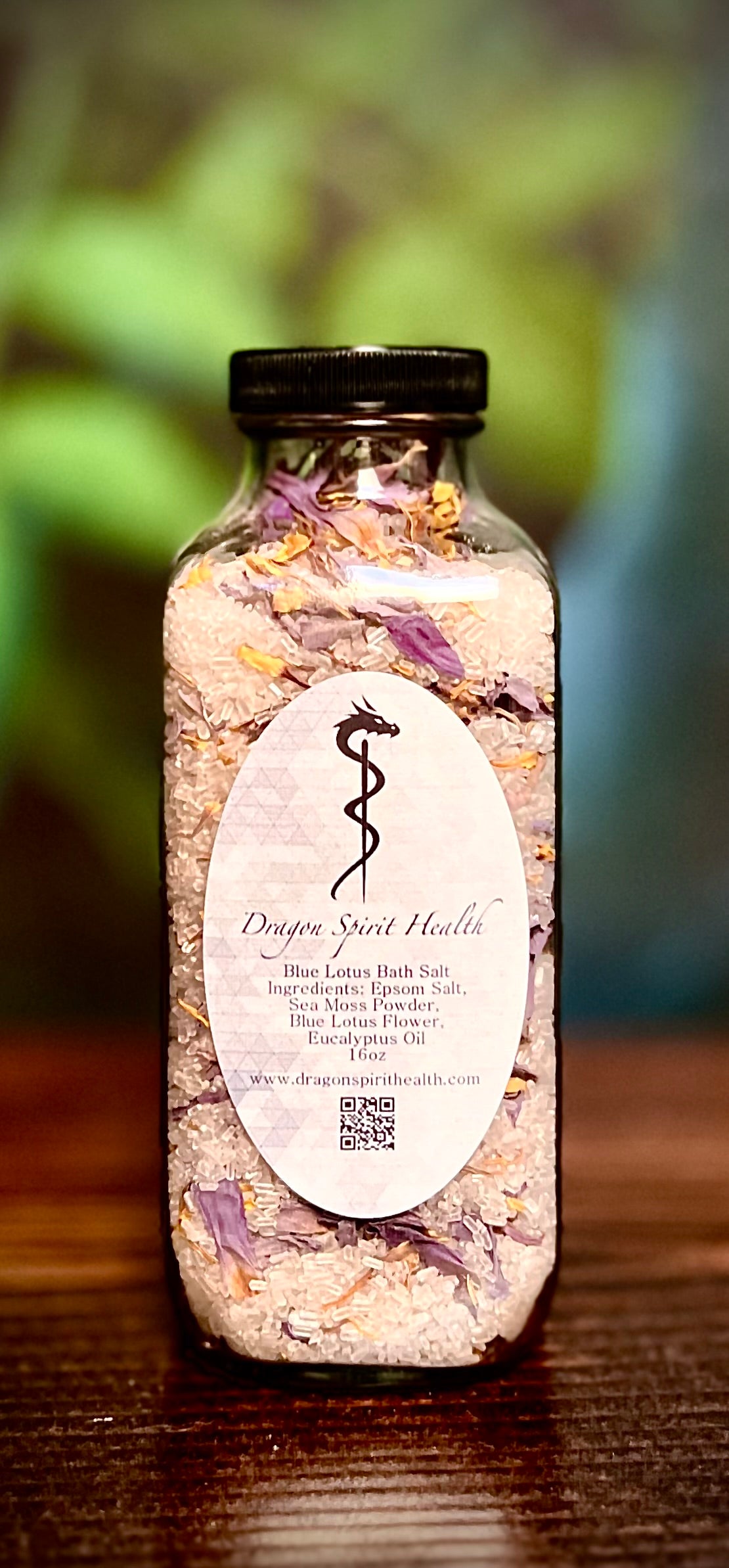 Bottle of Blue Lotus Sea Moss Infused Bath Salts with a label on a wooden surface